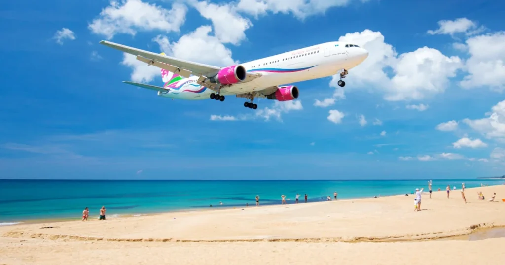 A flight landing on a beautiful beach with people in Thailand.