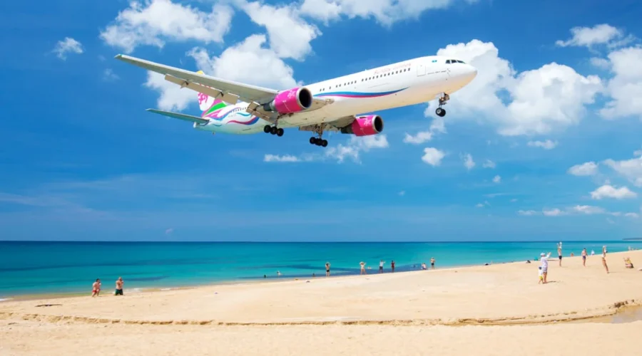 A flight landing on a beautiful beach with people in Thailand.